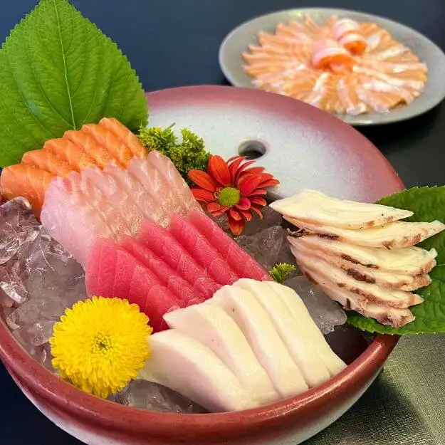 Tigela de sashimis de salmão, atum, peixe branco e polvo sobre gelo, pratos frios do rodízio